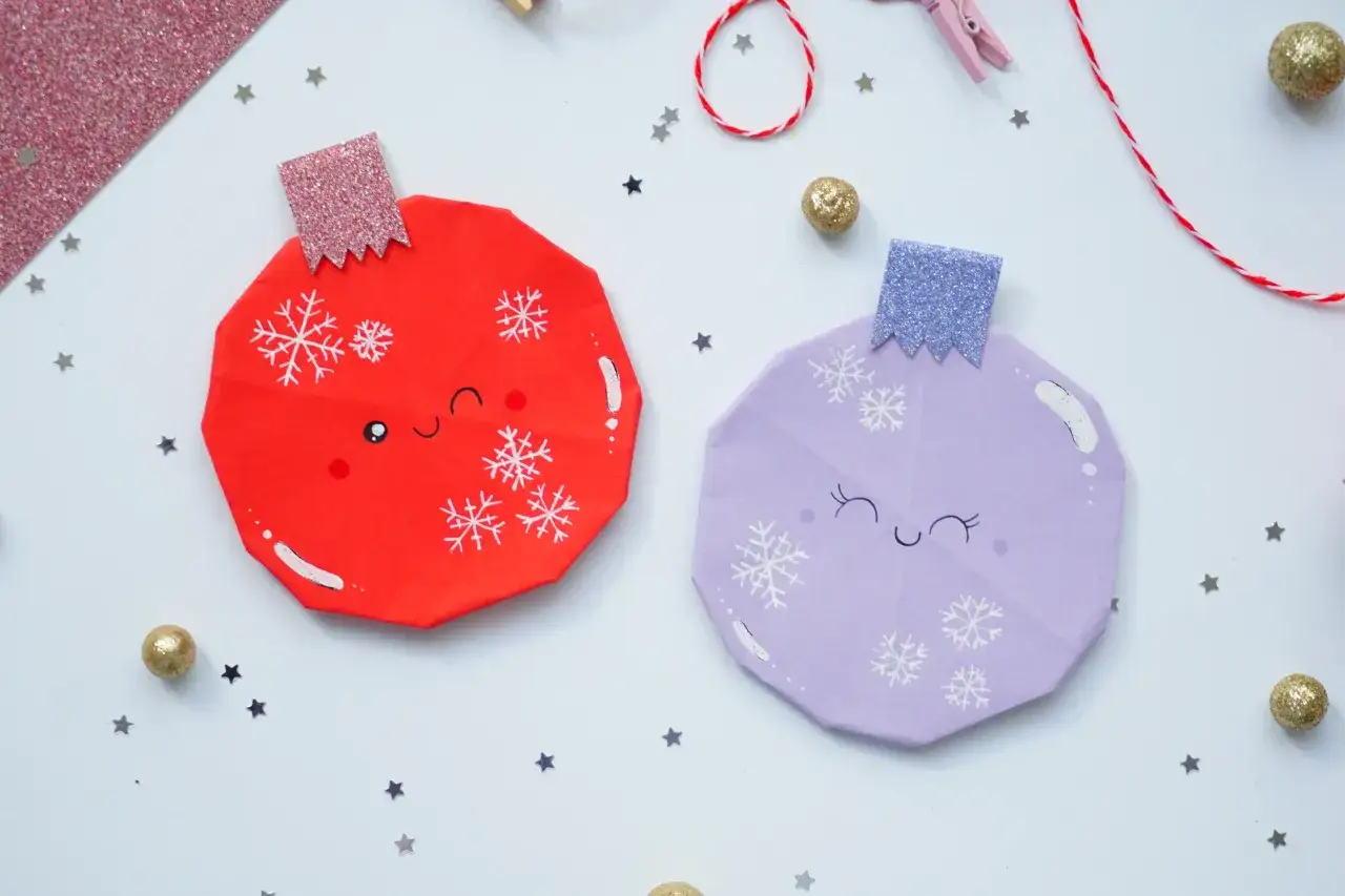 Urocze bombki z papieru dla dzieci, ozdobione płatkami śniegu i uśmiechniętymi buźkami, tworzą zimową atmosferę.