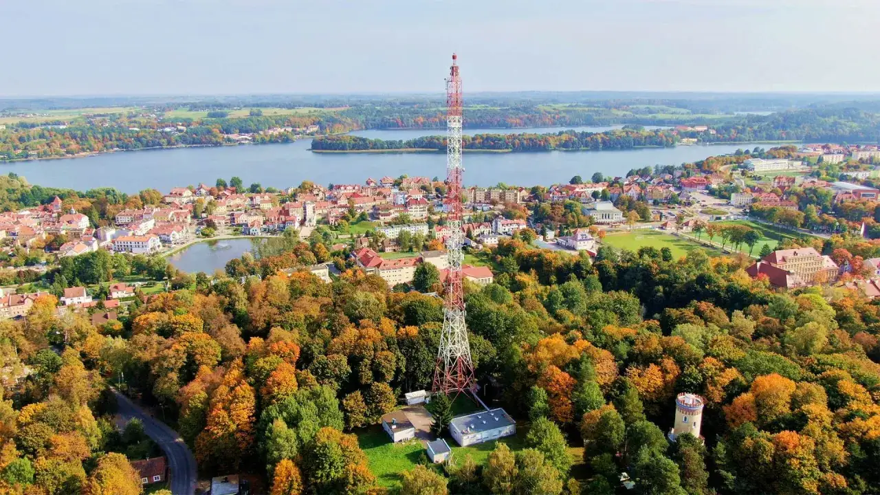 Widok na Mrągowo z wieżą radiową i jesiennymi drzewami. Jezioro i miasto tworzą piękne mrągowo atrakcje.