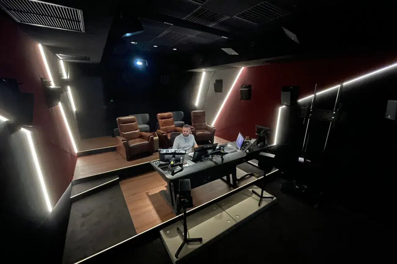 W nowoczesnym studiu nagraniowym Dream Sound Studios mężczyzna pracuje przy konsoli dźwiękowej, otoczony wygodnymi fotelami i futurystycznym oświetleniem.