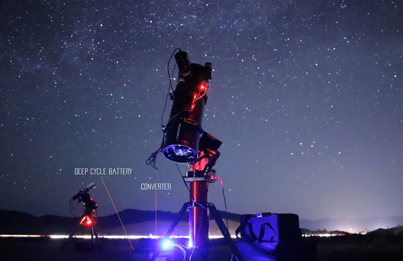 Profesjonalny teleskop do astrofotografii ustawiony pod rozgwieżdżonym niebem. Widać zasilanie i torbę.