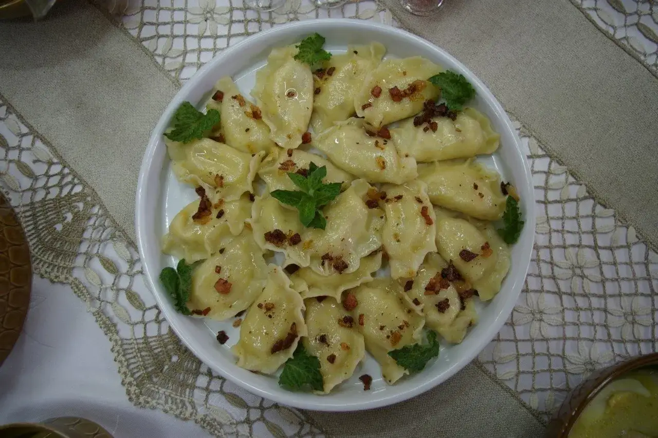 Talerz pełen pysznych pierog&oacute;w, polanych skwarkami i udekorowanych miętą. To prawdziwy catering jak u mamy, smak dzieciństwa na talerzu.