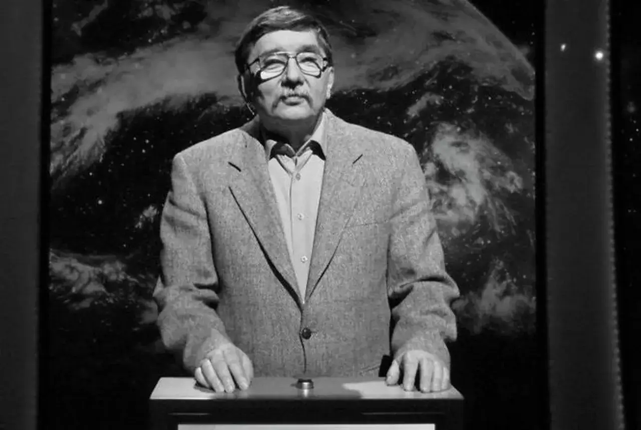 Tadeusz Szmuk, w okularach i marynarce, na tle kosmosu. Czy Tadeusz Szmuk żyje? Tak, wciąż inspiruje.