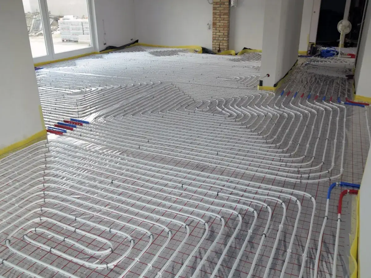 Salon 30 m2: pętle podłogówki ułożone na siatce. Widać białe rurki systemu grzewczego.