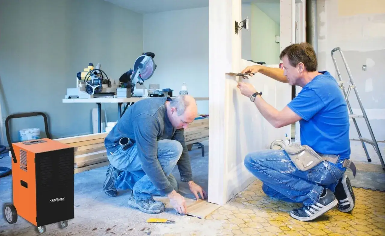 Pomarańczowe urządzenie do usuwania wilgoci stoi obok budowlańc&oacute;w pracujących przy remoncie.