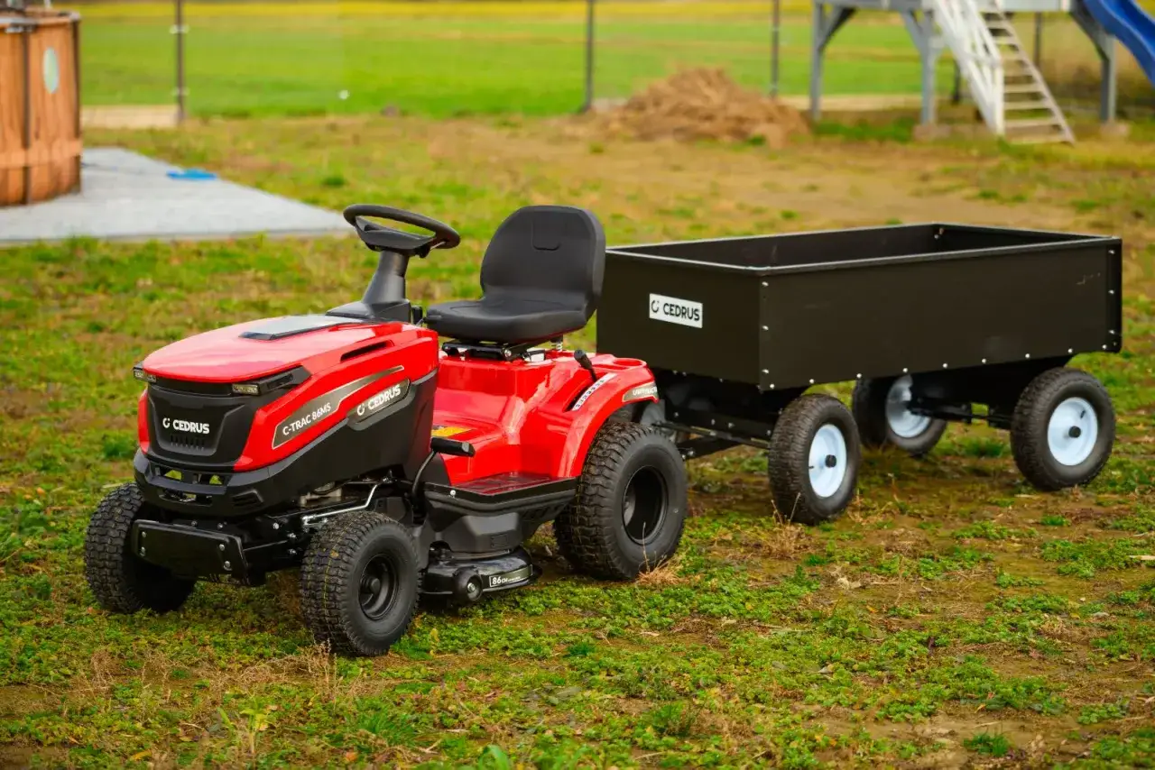 Czerwony ciągnik do koszenia trawy Cedrus z przyczepką, gotowy do pracy w ogrodzie.
