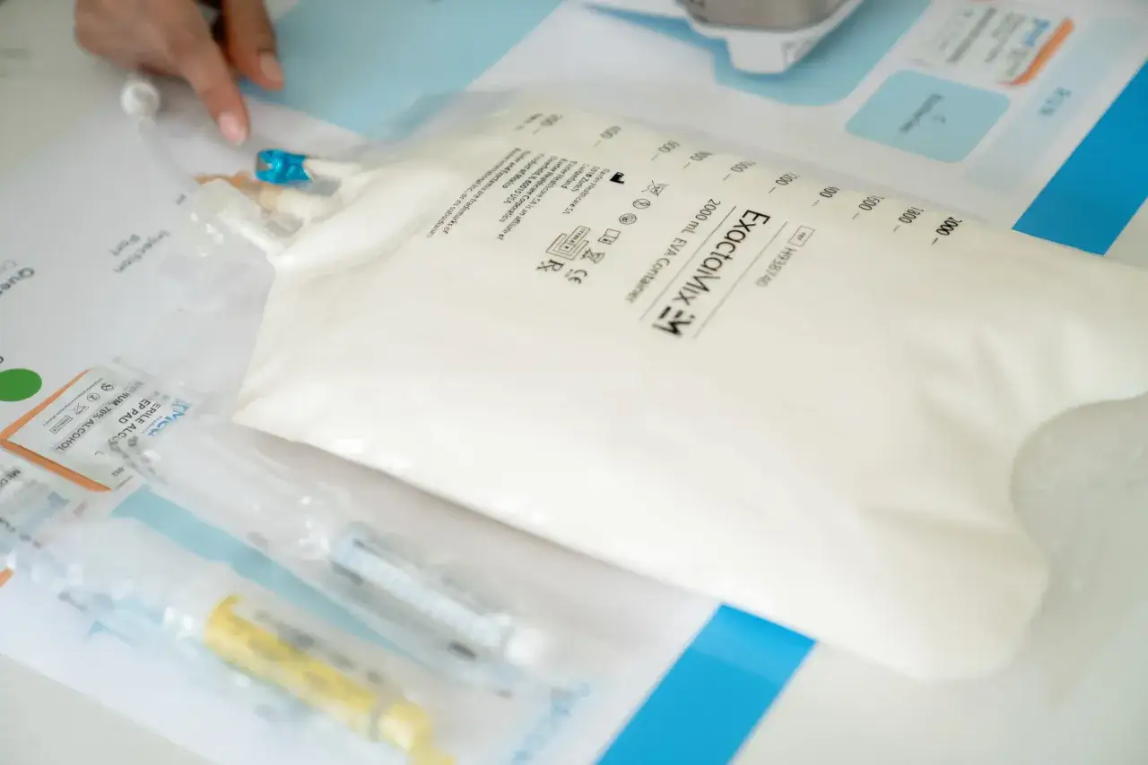 Worek z płynem do żywienia pozajelitowego ExactaMix, gotowy do podania. Obok widać materiały medyczne.