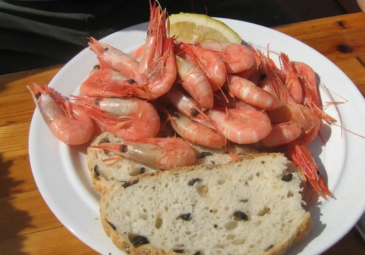 Gotowane krewetki na talerzu z chlebem i cytryną. Idealne do prostego przepisu na krewetki gotowane.