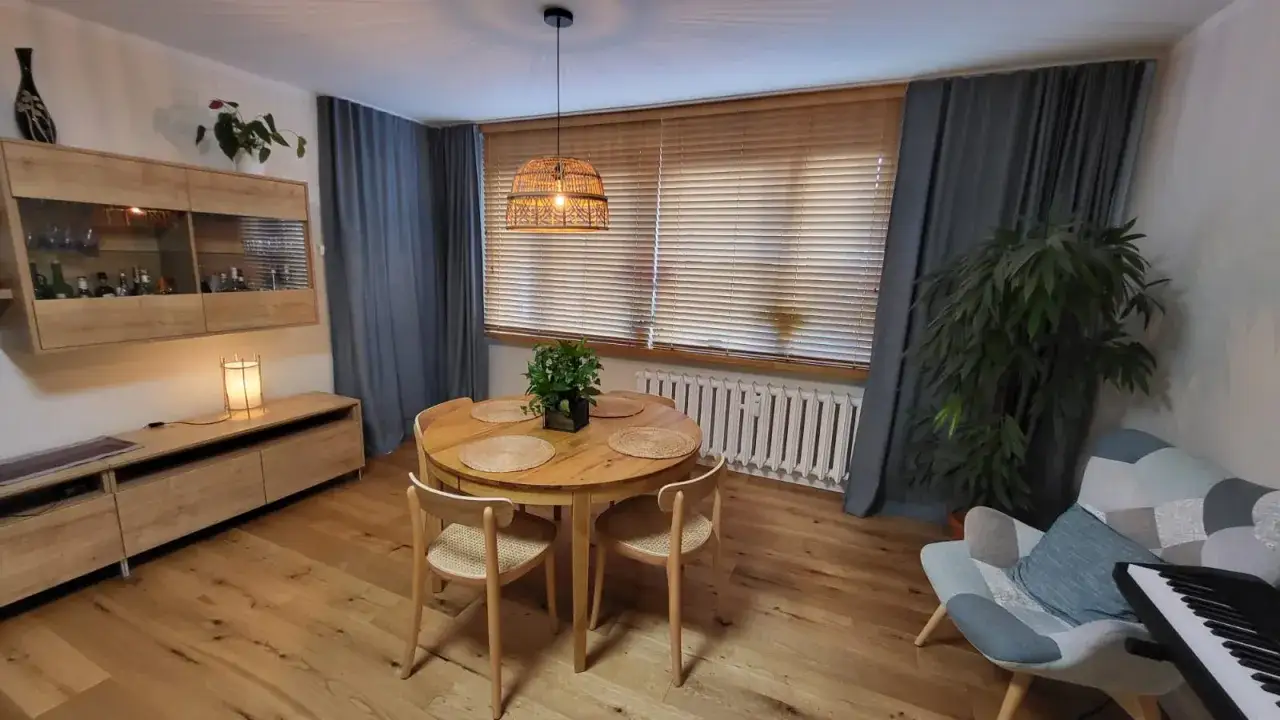 Nowoczesne zasłanianie okien: drewniane żaluzje i szare zasłony tworzą przytulną atmosferę jadalni.