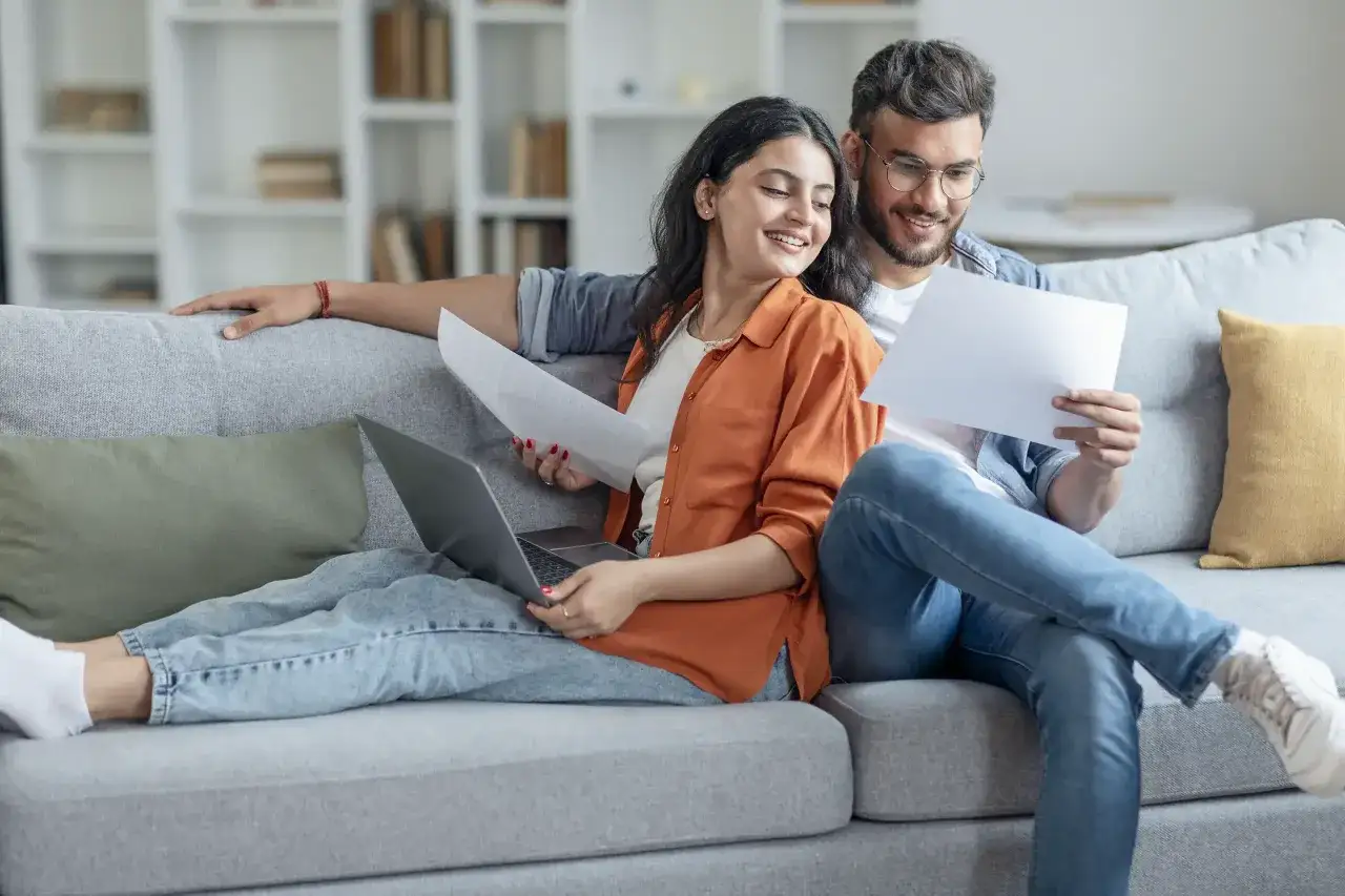 Para omawia dokumenty na kanapie, planując rozdzielność majątkową po ślubie.