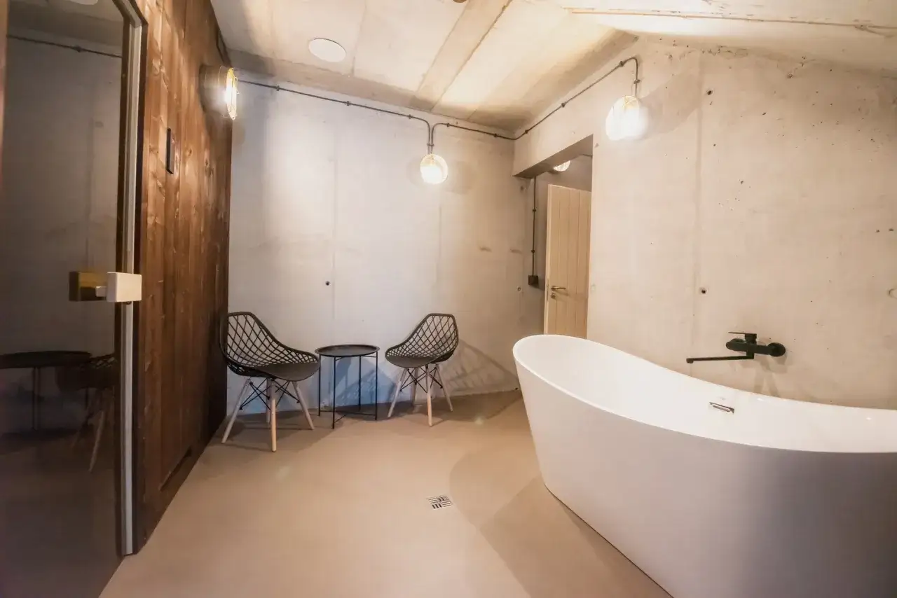 Nowoczesna łazienka z wolnostojącą wanną i betonowymi ścianami. Mikrocement w łazience tworzy minimalistyczny, surowy klimat.