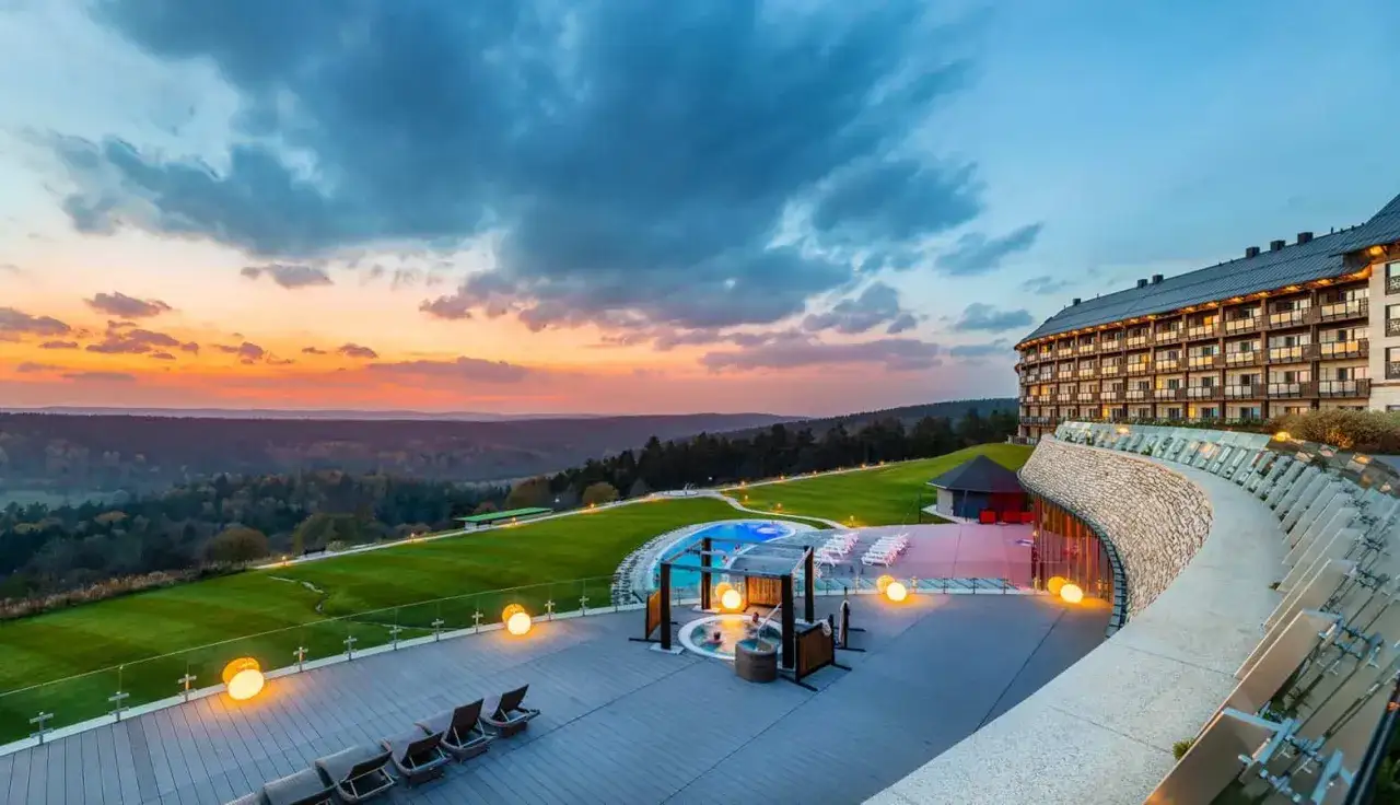 Luksusowy hotel w Bieszczadach z basenem i jacuzzi, otoczony zielonymi wzgórzami, w blasku zachodzącego słońca.