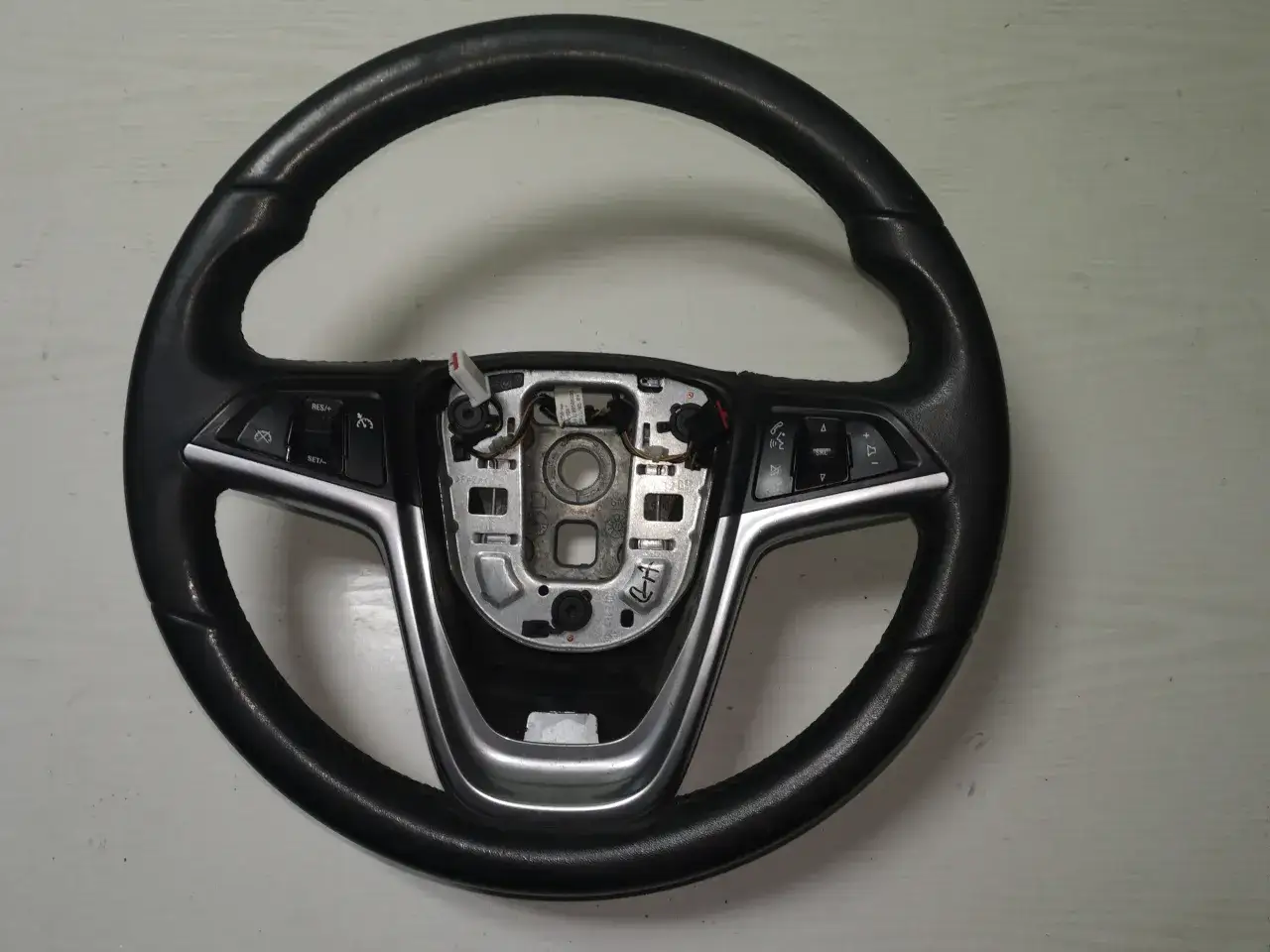 Czarna kierownica Opel Astra J z przyciskami sterowania radiem i tempomatem.