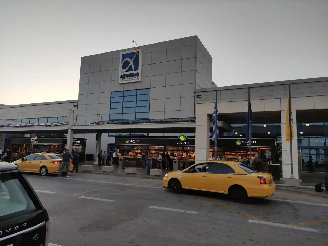 Port lotniczy Ateny. Żółte taksówki czekają na pasażerów przed nowoczesnym terminalem.