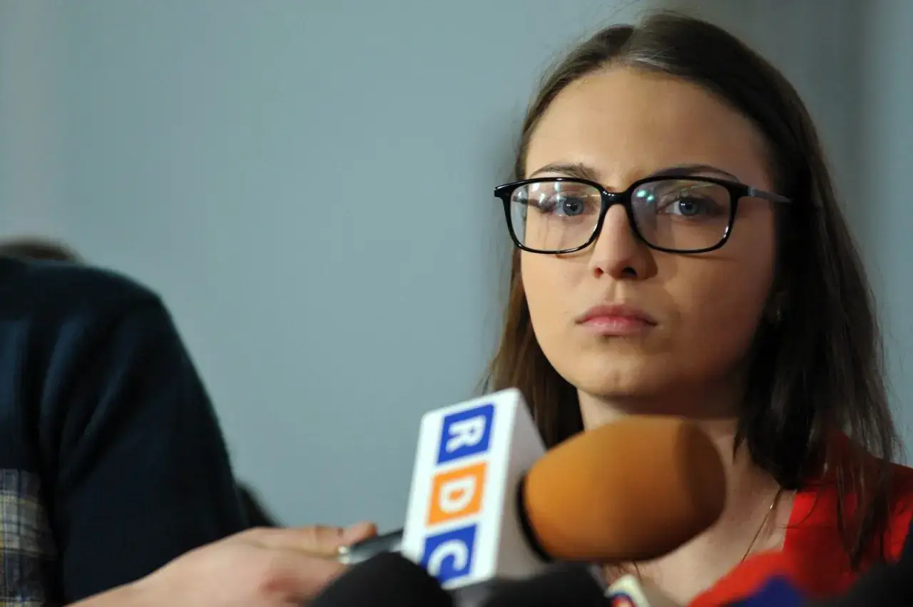 Posłanka Kinga Gajewska w okularach udziela wywiadu przed mikrofonami RDC.