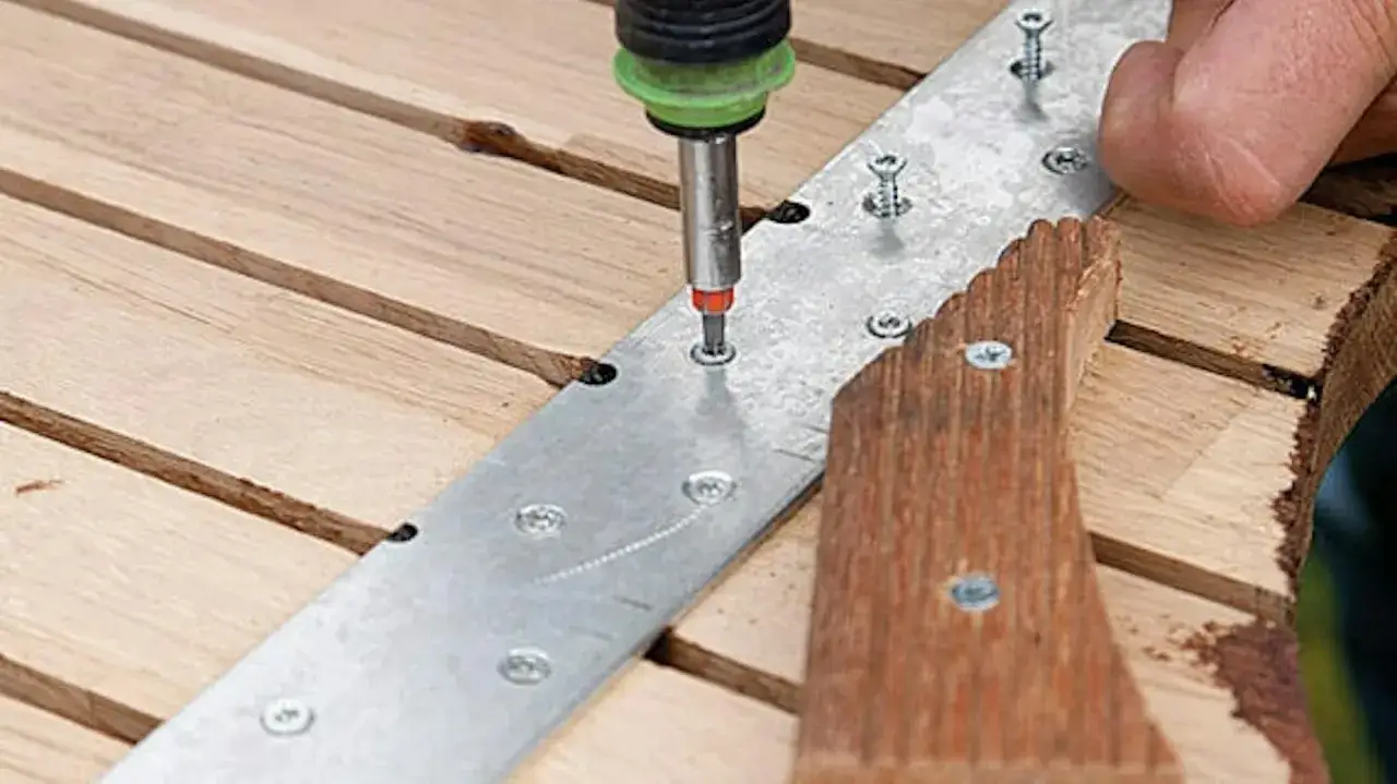 Montaż drewnianej ławki ogrodowej: przykręcanie metalowej płaskownika do desek.