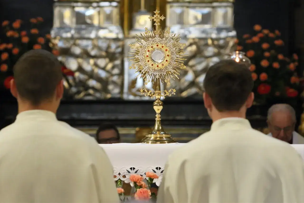 Uroczystość Najświętszego Ciała i Krwi Chrystusa. Monstrancja z Hostią na ołtarzu, przed nią klęczą ministranci.