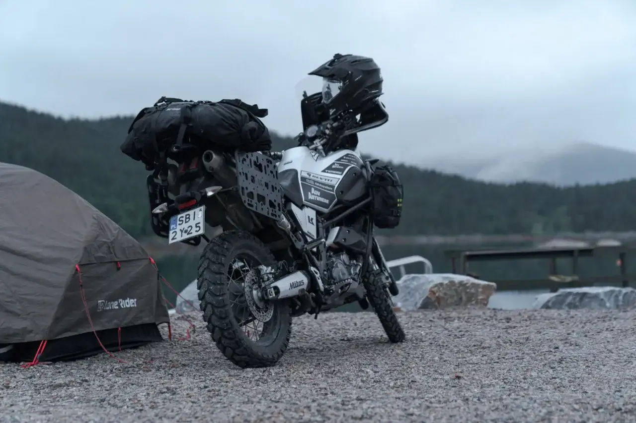 Motocykl turystyczny z sakwami i kaskiem obok namiotu. Idealny zestaw, jaki namiot na motocykl sprawdzi się w podr&oacute;ży?