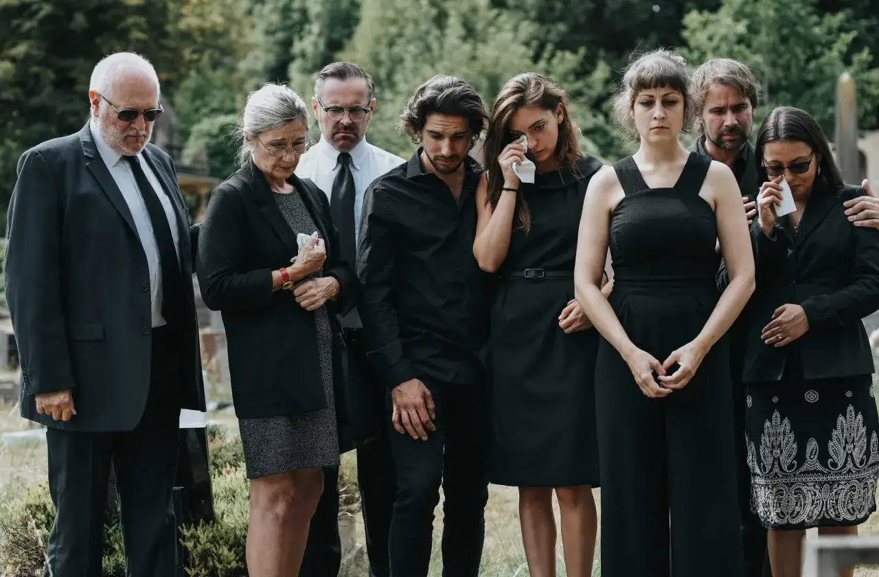 Smutna rodzina w czerniach, zastanawiająca się, ile trwa pogrzeb. Wzruszające chwile żałoby na cmentarzu.