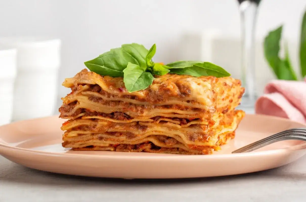 Pyszna, wielowarstwowa lasagne z mięsnym sosem i bazylią na talerzu. Idealna alternatywa dla cannelloni.