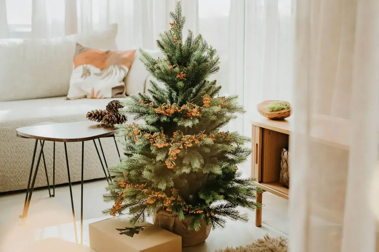 Ozdoby świąteczne na choince, gotowe do schowania. W tle kanapa i stolik z szyszkami.