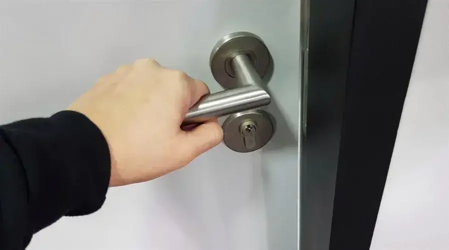 osoba sprawdzająca klamkę drzwi, zamek