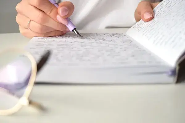 Osoba prowadząca dziennik, pisząca w notatniku, symbolizująca refleksję i samorozw&oacute;j