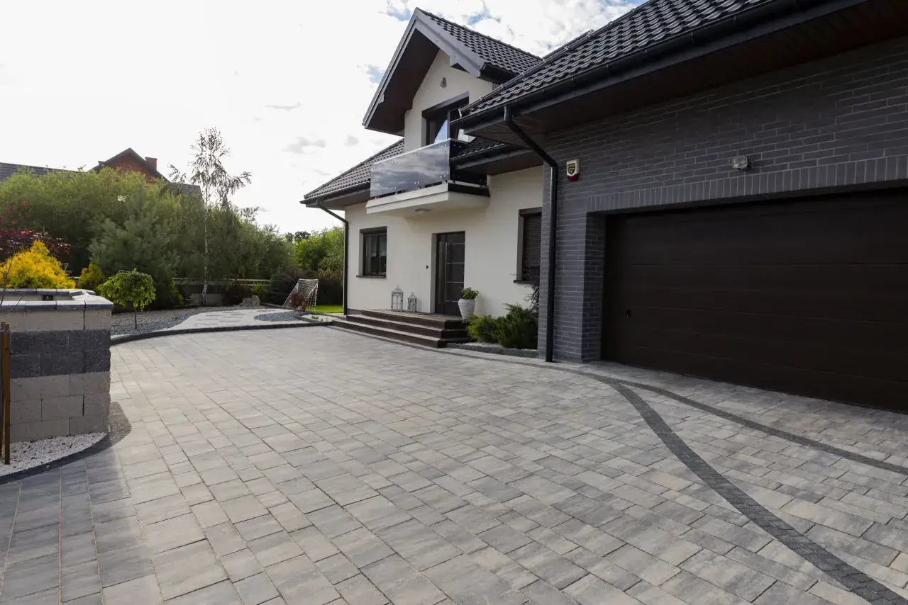 Nowy podjazd z kostki brukowej prowadzi do nowoczesnego domu z garażem.