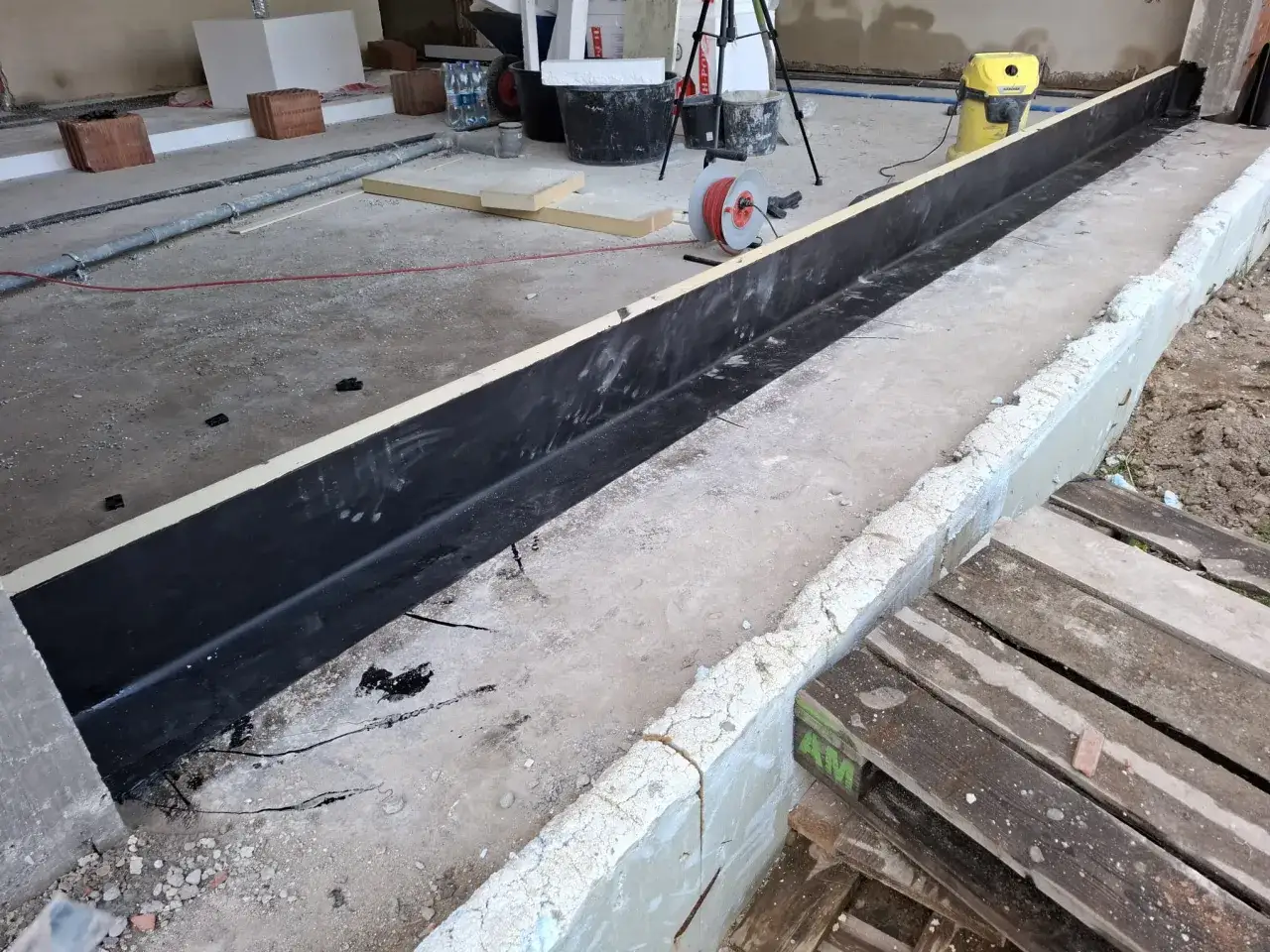 Przygotowania do montażu ciepłego progu bramy garażowej. Czarna membrana hydroizolacyjna czeka na swoje miejsce.