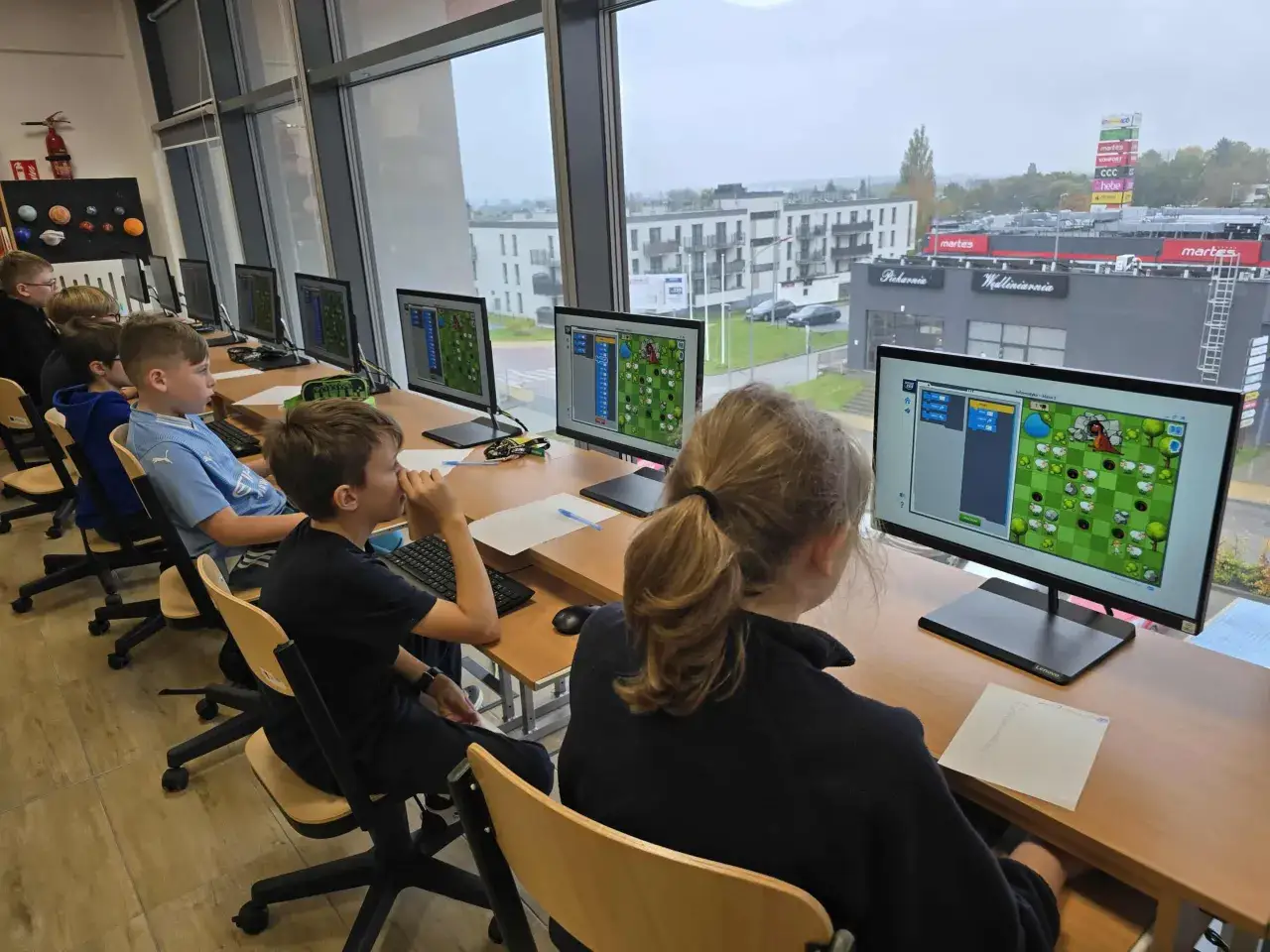 Uczniowie klasy 1 informatyka programują grę na komputerach.