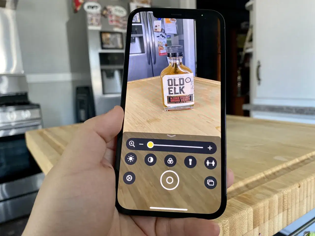 Telefon z funkcją **lupa w telefonie** zbliża małą buteleczkę bourbonu Old Elk.