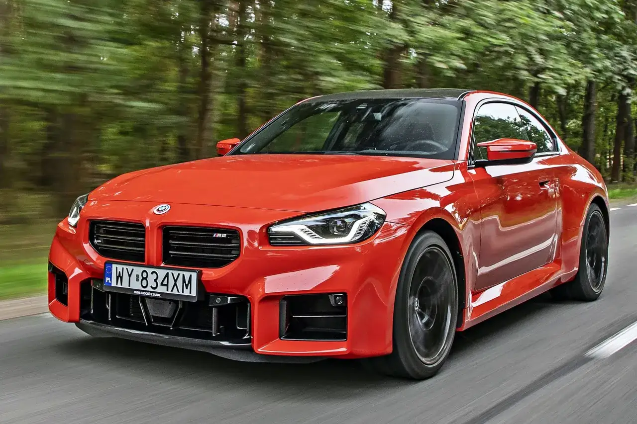 Pomarańczowe BMW M2 pędzi leśną drogą. Sprawdź aktualną bmw m2 cena i możliwości tego sportowego coupe.