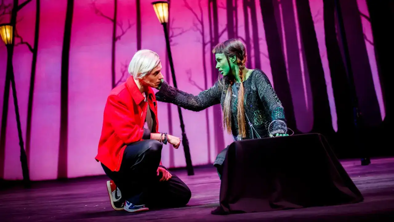 Na scenie mężczyzna w czerwonej kurtce klęczy przed zielonoskórą kobietą, która dotyka jego policzka. Czy to początek ich historii, czy może już wiedzą, jak długo będą razem w tej opowieści?