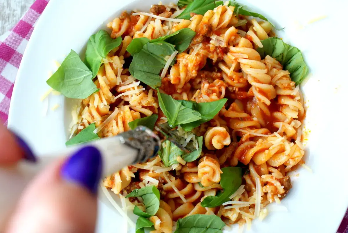 Pyszne fusilli z sosem bolońskim i bazylią, posypane parmezanem. Czy wolisz fusilli czy penne?