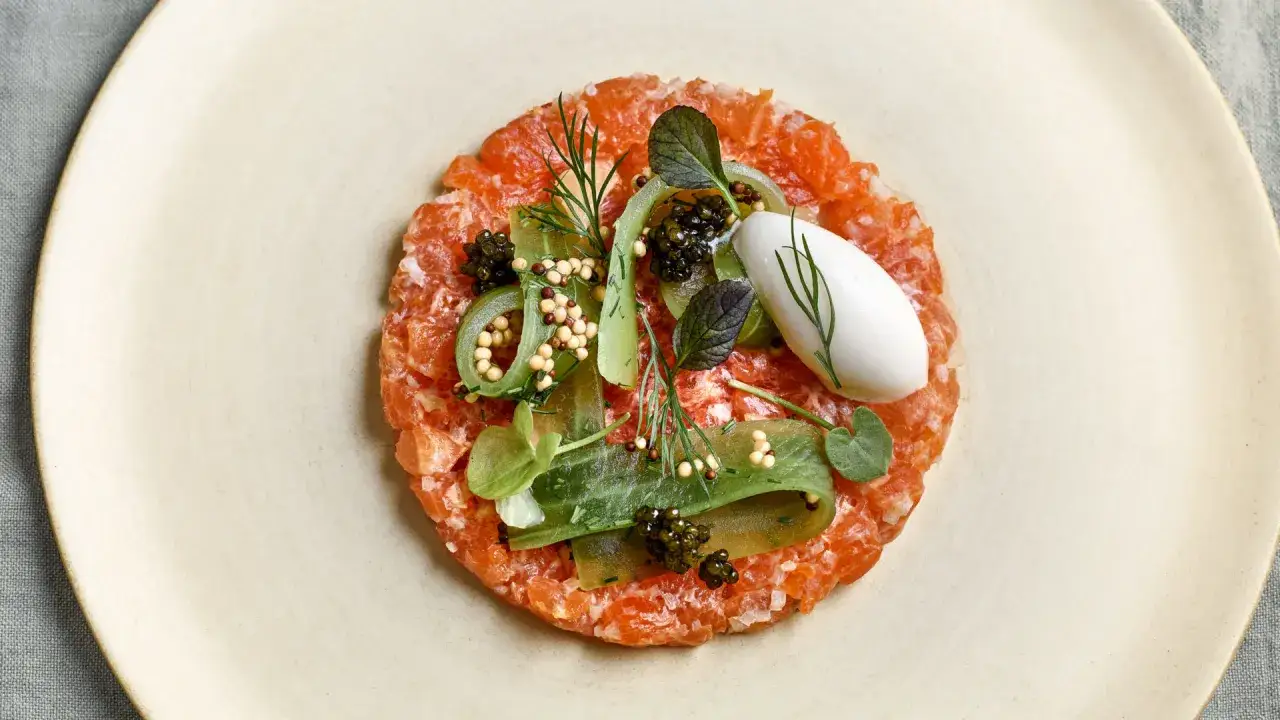 Wykwintny tatar z łososia z kawior, ogórkiem, musztardą i delikatną pianką.