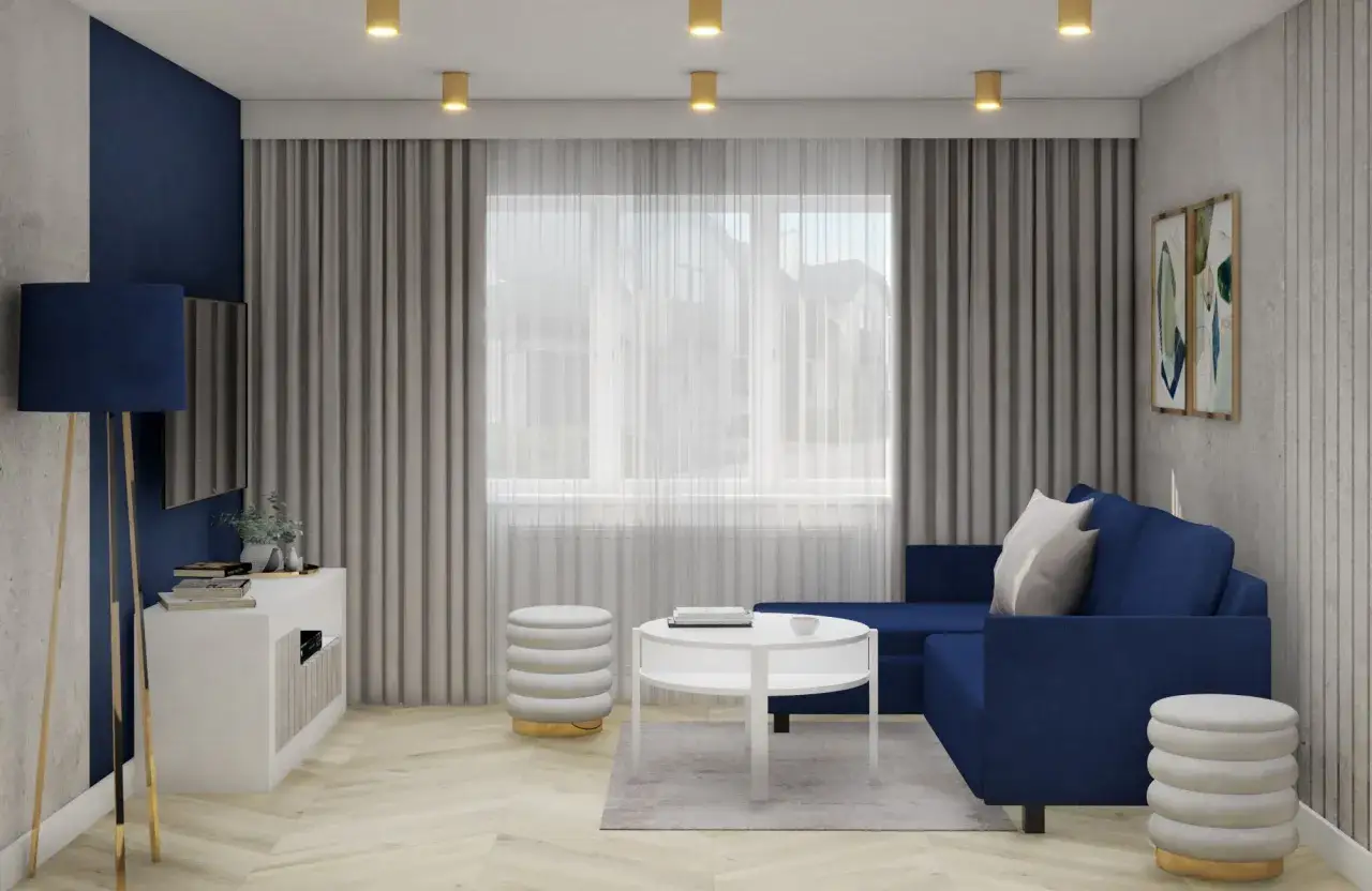 Elegancki salon w odcieniach beżu z granatem. Granatowa kanapa i lampa stojąca kontrastują z jasnymi ścianami i zasłonami.
