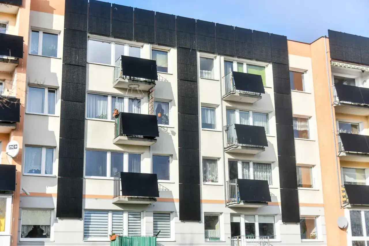 Nowoczesna fotowoltaika w bloku mieszkalnym. Panele słoneczne zamontowane na elewacji i balkonach, zapewniające zieloną energię.