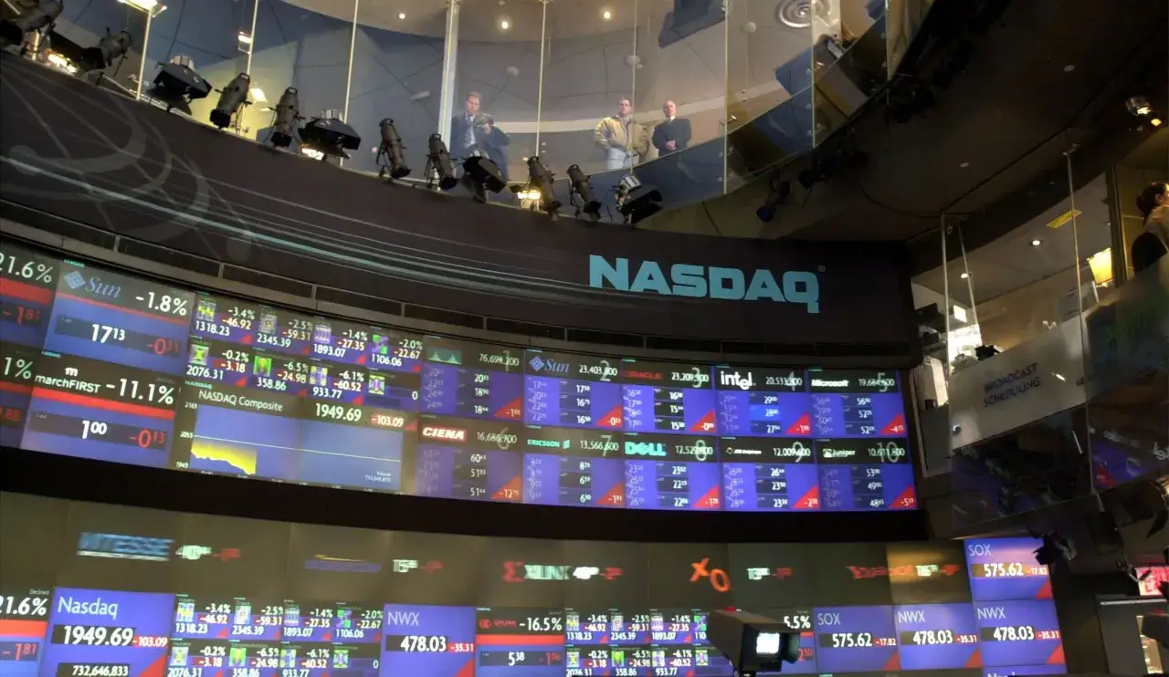Wielkie ekrany z danymi giełdowymi, logo NASDAQ. To miejsce, gdzie można dowiedzieć się, nasdaq co to jest i jak działa rynek.