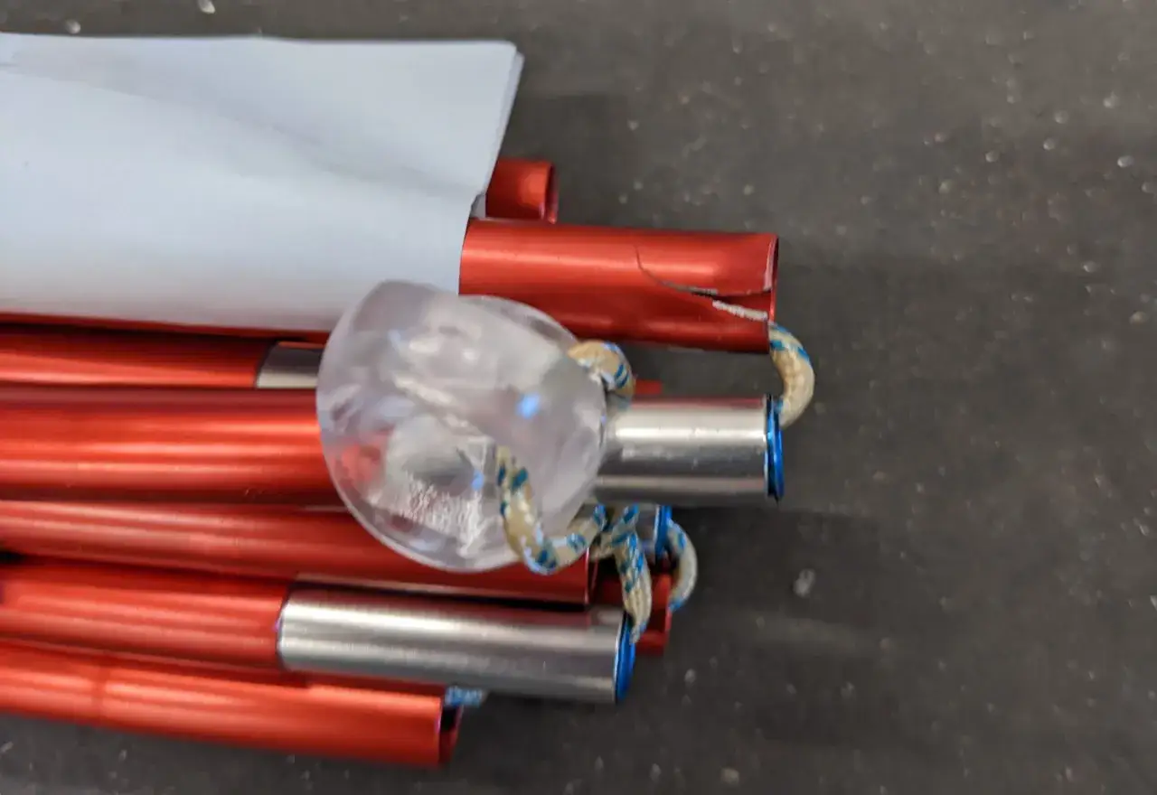 Część namiotu: czerwone aluminiowe pałąki połączone linką, z przezroczystą końc&oacute;wką.