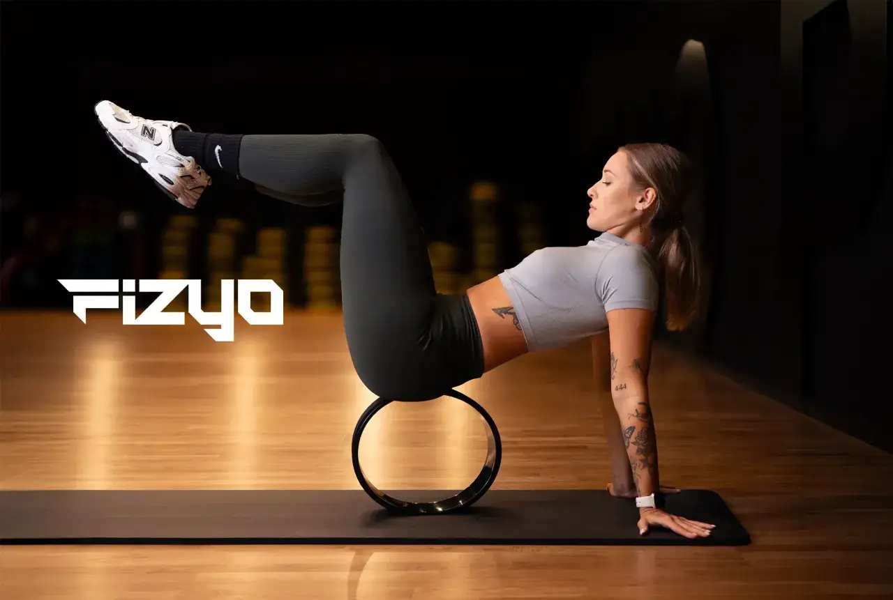 Kobieta ćwiczy pilates na macie z użyciem koła, wzmacniając mięśnie. To pokazuje, co daje pilates: siłę i elastyczność.