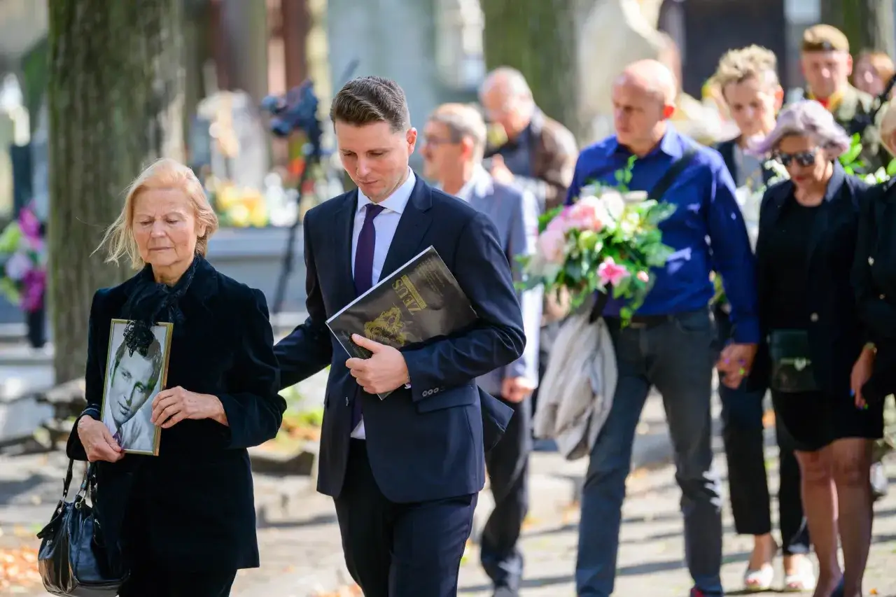 Pogrzeb Eugeniusza Korczarowskiego. Kobieta niesie portret zmarłego, mężczyzna trzyma książkę.