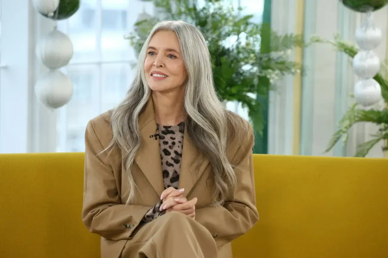 Elegancka kobieta z siwymi włosami w beżowym garniturze i bluzce w panterkę. Inspiracja, jak nosić siwe włosy z klasą.