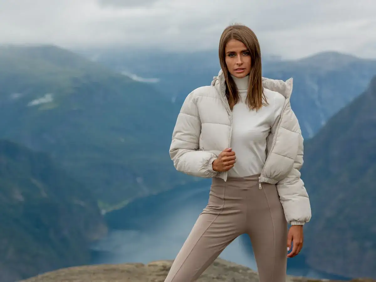Krótka kurtka puchowa w kremowym kolorze, idealna do stylizacji na tle górskiego krajobrazu.