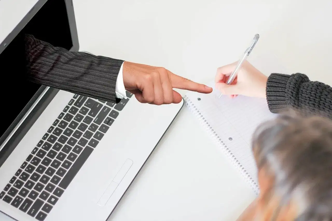 Ręka z laptopa wskazuje na notatki. Czy darmowe treści celebryty są lepsze niż jego płatny kurs premium?