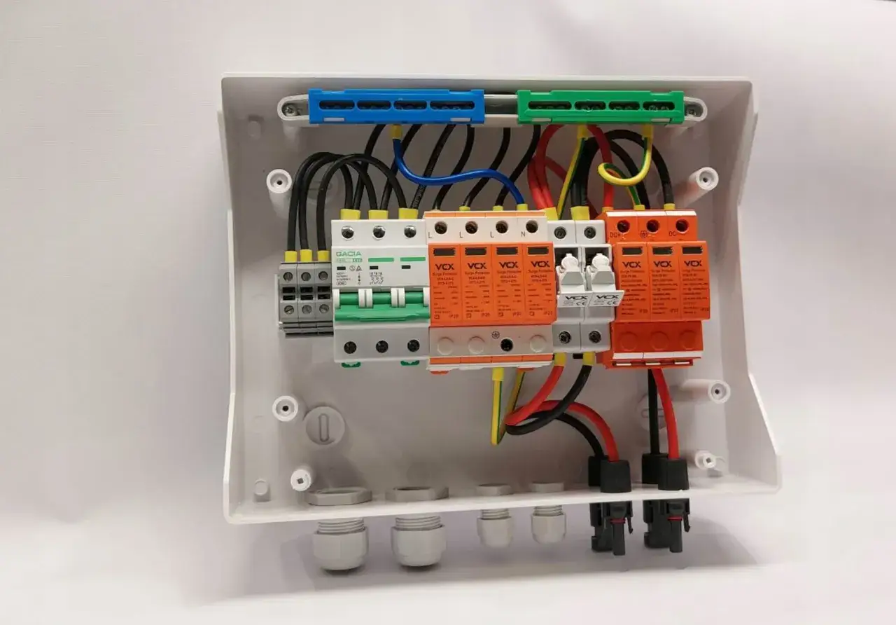 Schemat podłączenia zabezpieczeń w skrzynce, pokazujący, jak rozdzielić prąd tr&oacute;jfazowy. Widoczne wyłączniki i ochronniki przeciwprzepięciowe.
