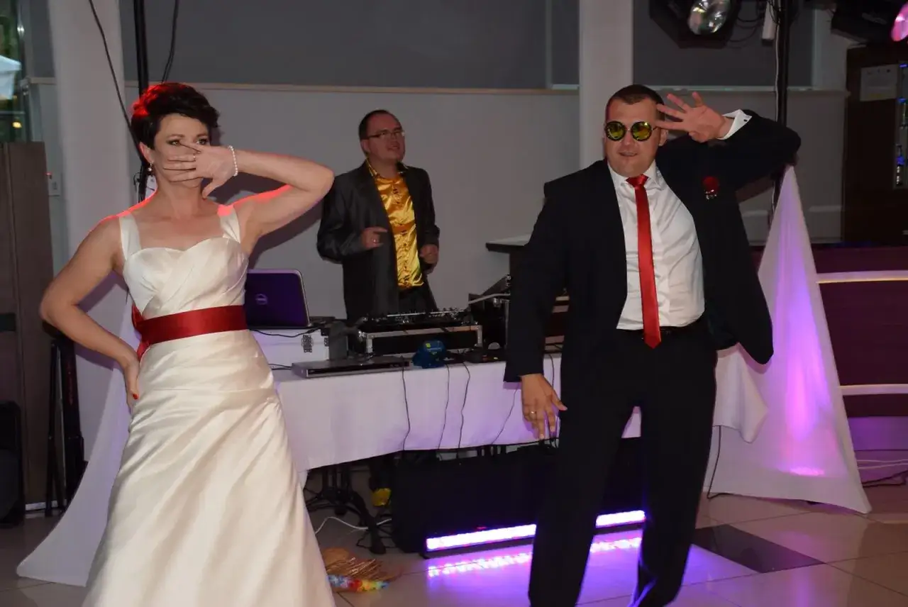 Panna młoda i pan młody tańczą na weselu, DJ gra muzykę. Wszyscy świetnie się bawią, pokazując, jak tańczyć na weselu.