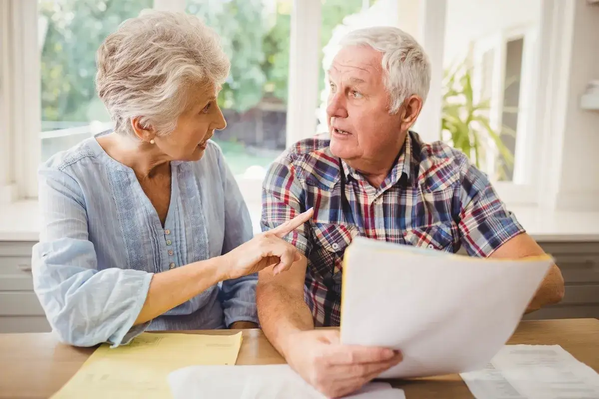Starsza para dyskutuje o dokumentach, zastanawiając się, co to jest okresowa emerytura kapitałowa.