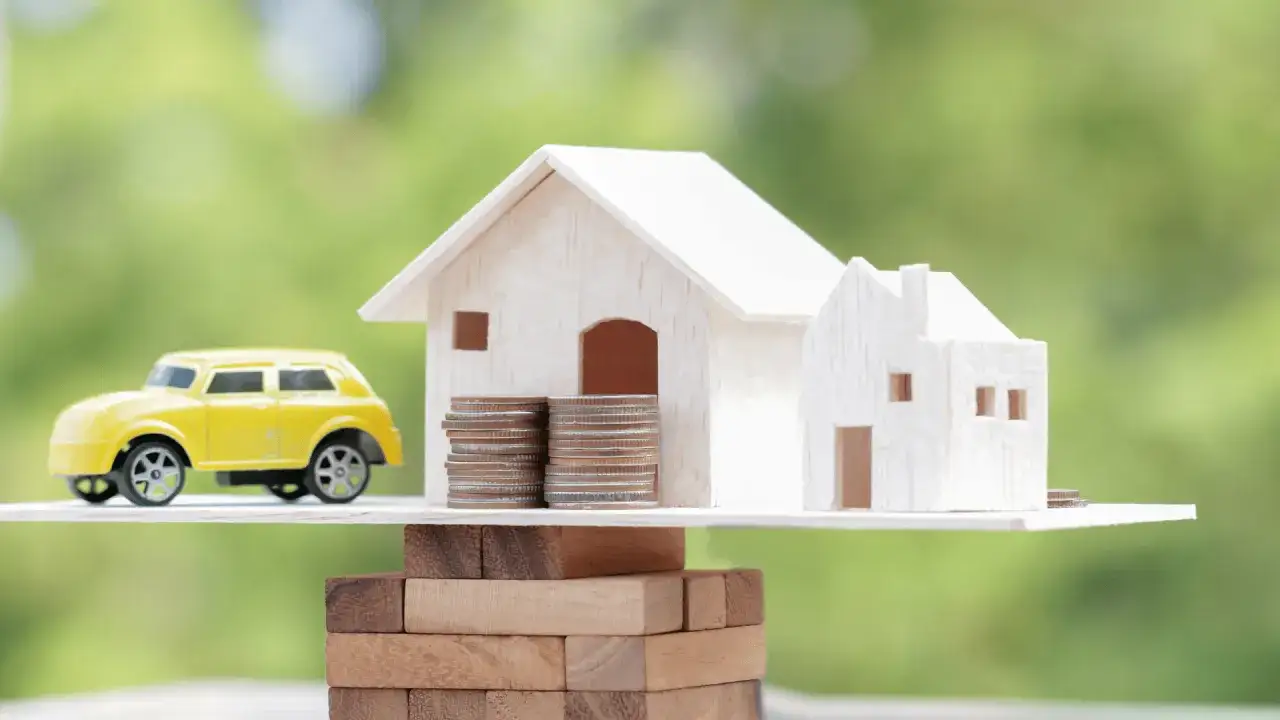 Model domu i żółtego samochodu na stosie monet, symbolizujące kaucję gwarancyjną leasing.