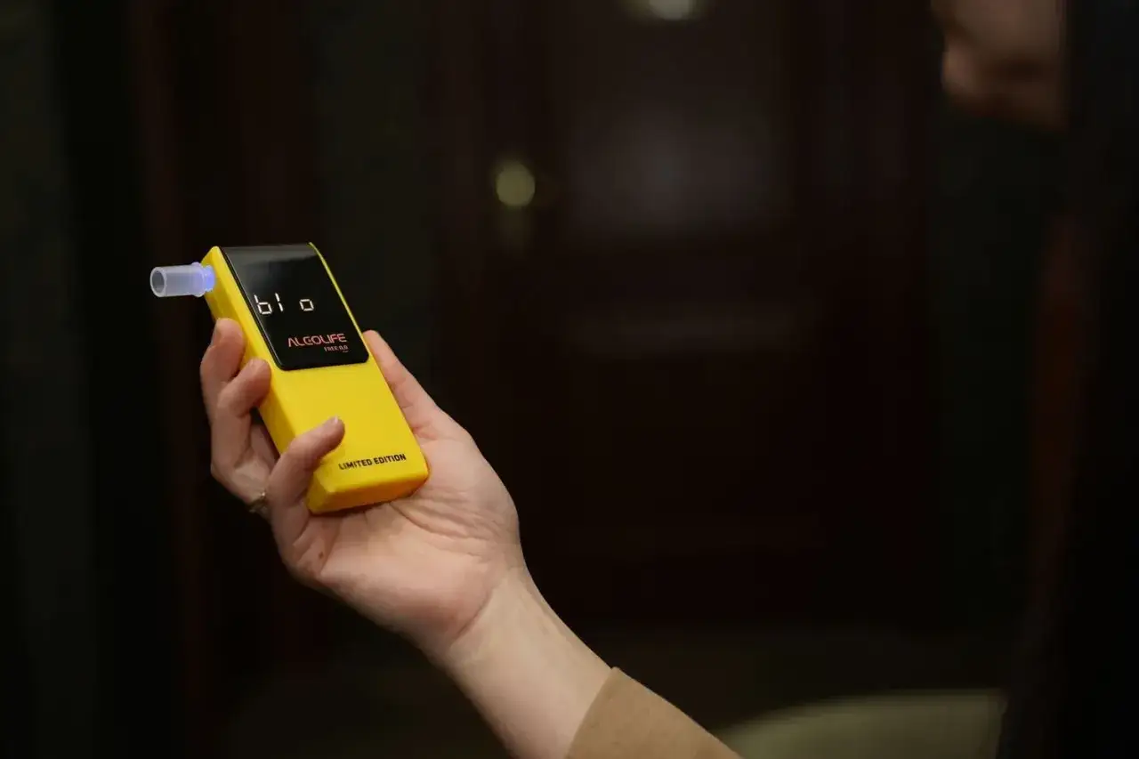 Dłoń trzyma żółty alkomat z napisem 