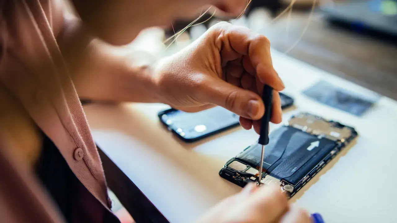 Technik serwisujący smartfon w punkcie obsługi klienta