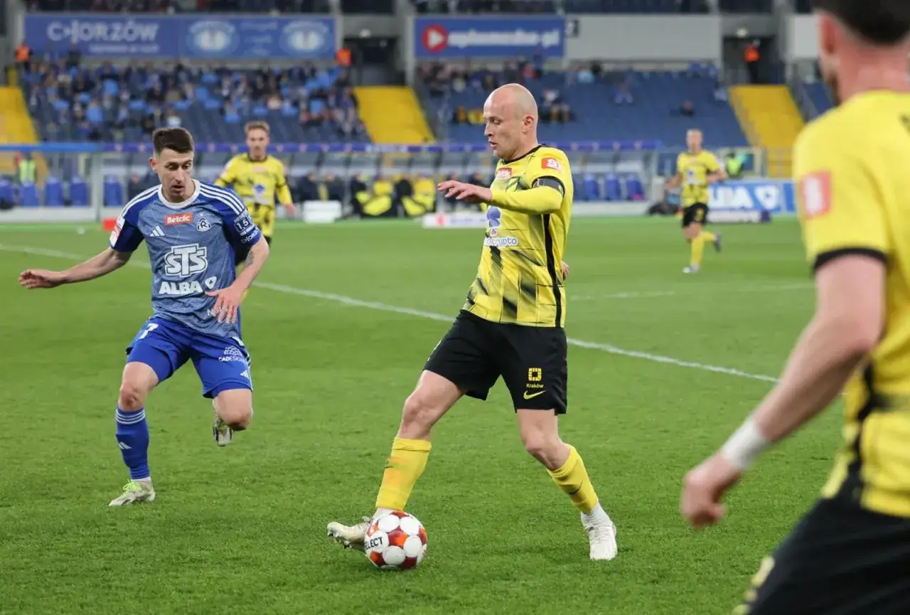 Piłkarze walczą o piłkę na boisku, decydując, kto awansuje do ekstraklasy.